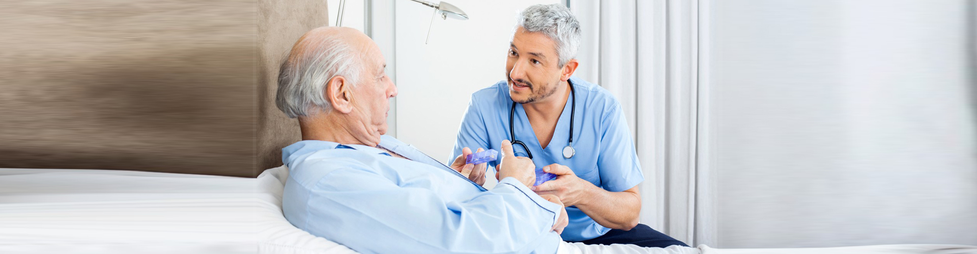 nurse holding medicine talking to patient in the bed